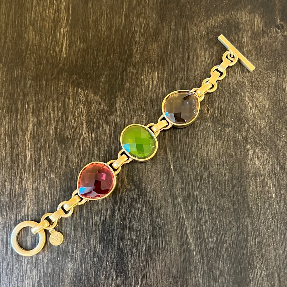 AK statement bracelet in flat gold tone.